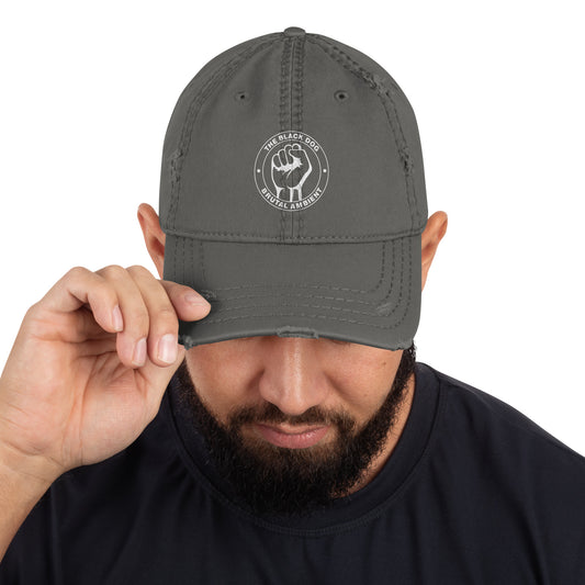 A man wearing a grey cap with a Brutal Ambient logo, holding it up to his head.