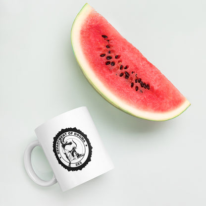 White mug with a black logo next to a slice of watermelon on a light gray background